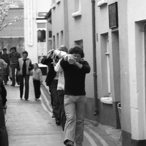 men carrying maypole through street