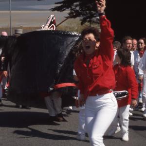 Woman dancing in front of Old Oss, with view of sea behind