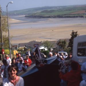Old Oss walking up hill with view of sea in distance