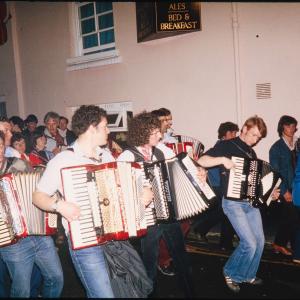 accordion players playing in procession at night