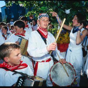 Children playing drums and accordions under maypole