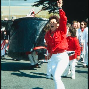 Woman dancing in front of Old Oss, with view of sea behind