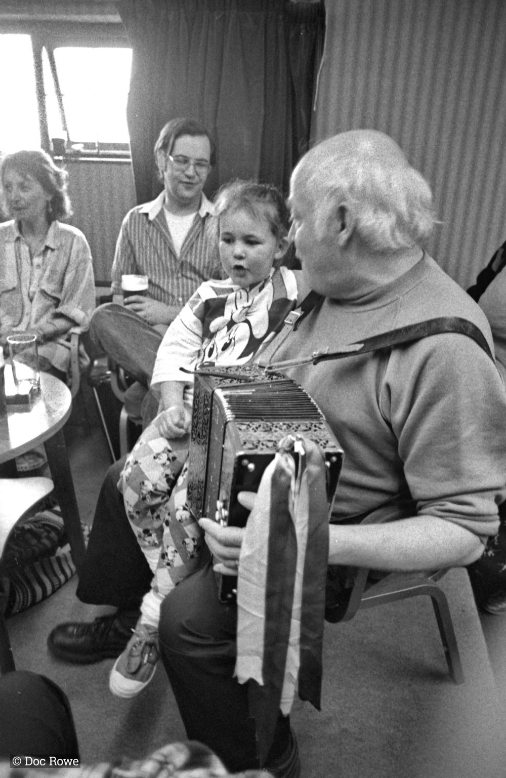 man playing accordion w girl on his knee