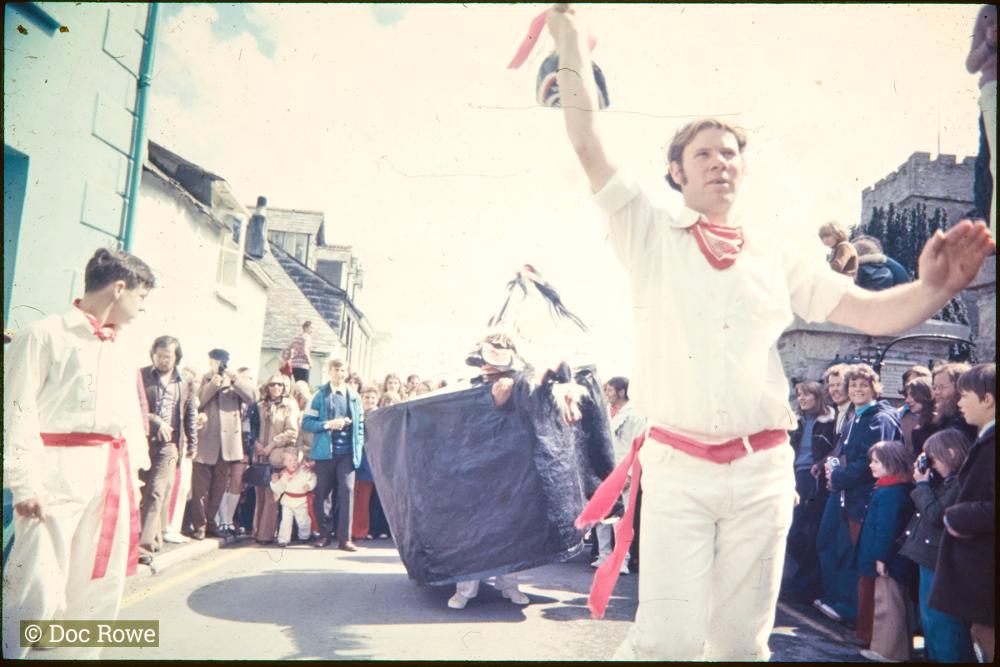 Teaser holding up club with Old Oss behind and crowd of spectators circled around