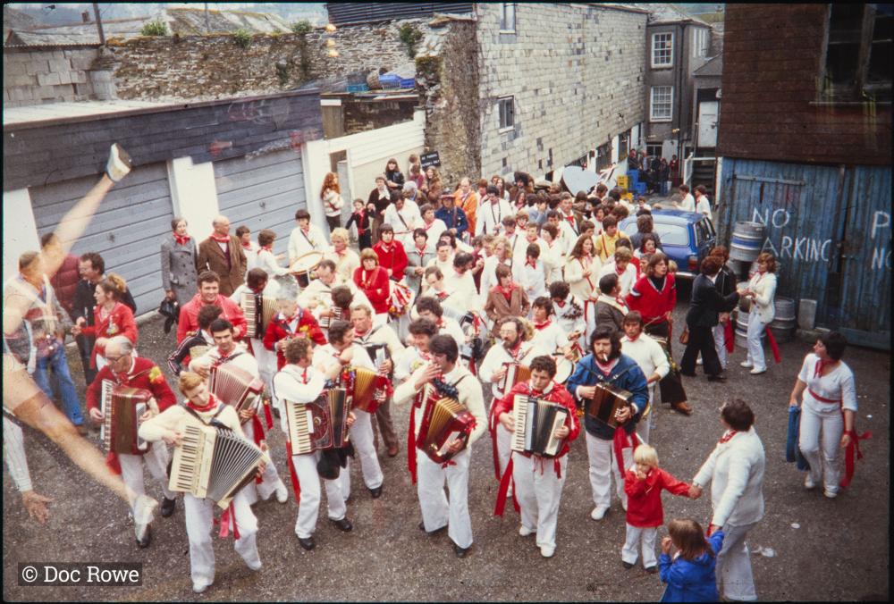 Old Oss procession walking up back road, led by accordions 