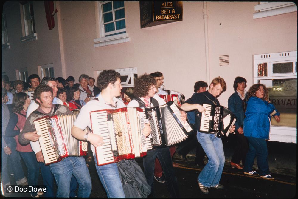 accordion players playing in procession at night