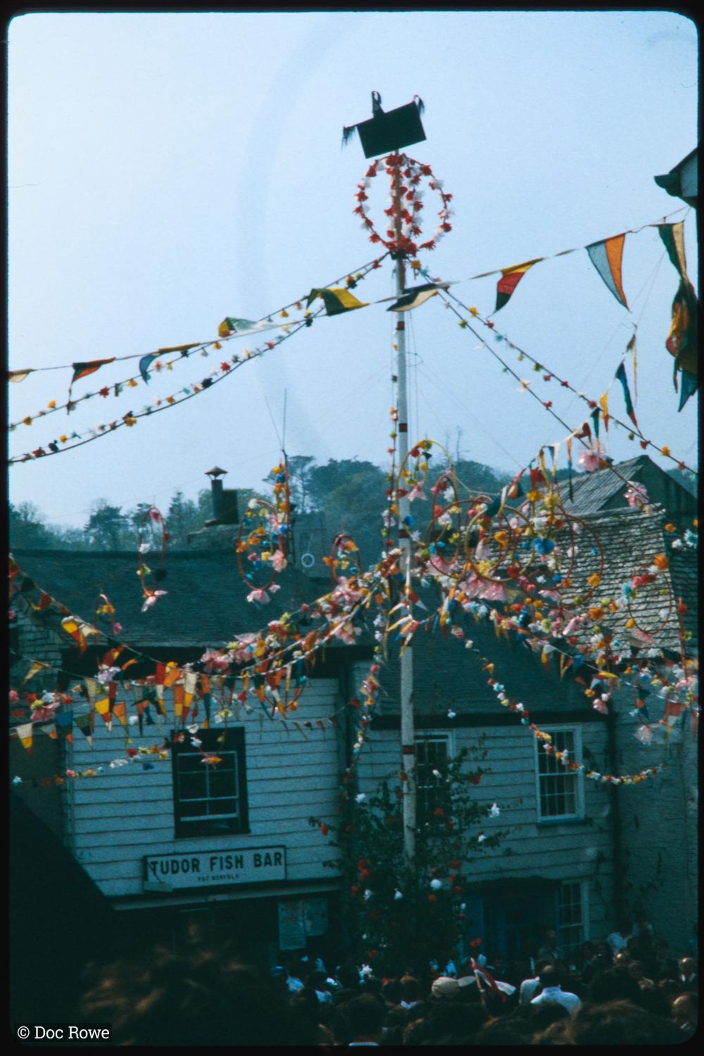 Maypole in evening with crowd beneath