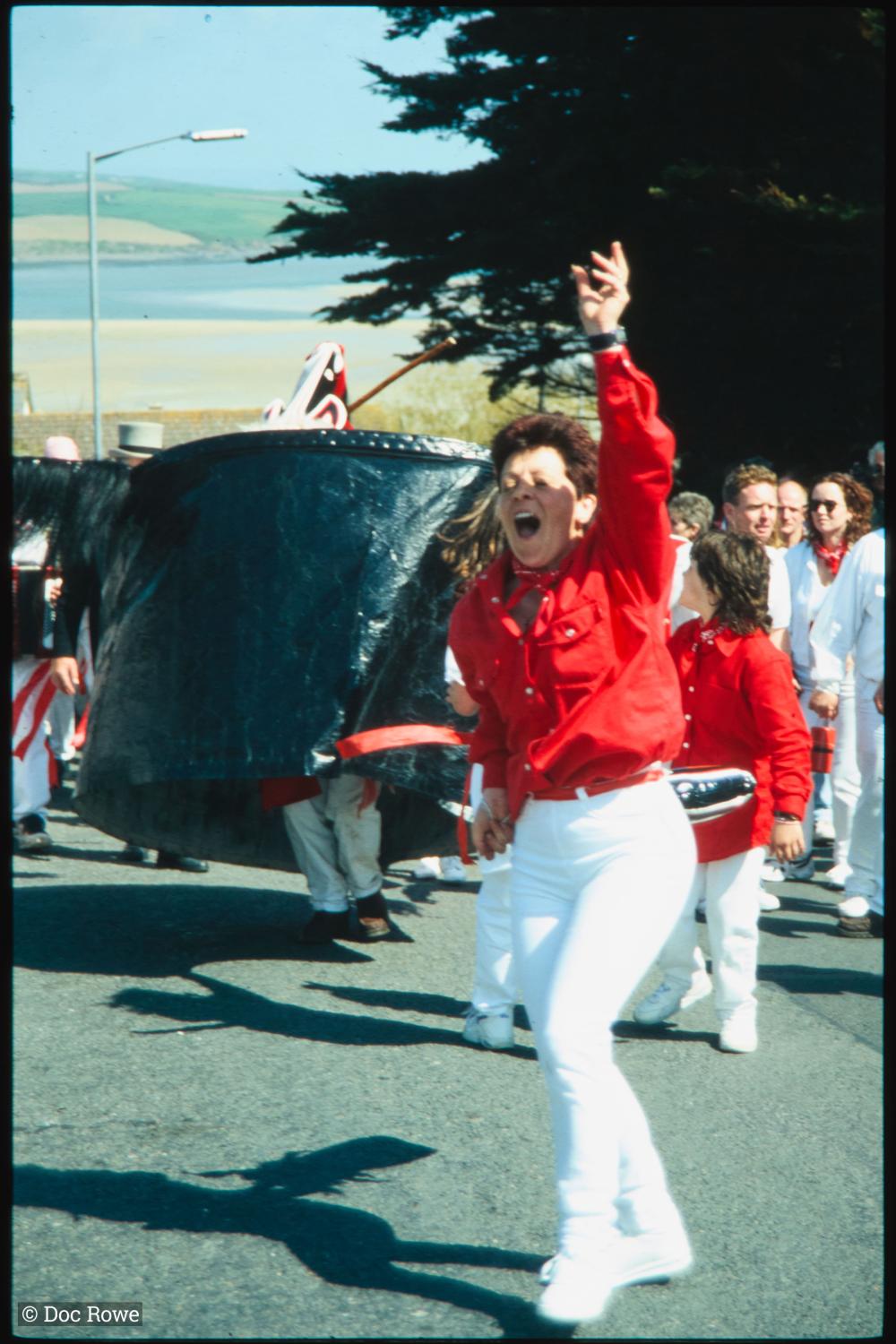 Woman dancing in front of Old Oss, with view of sea behind