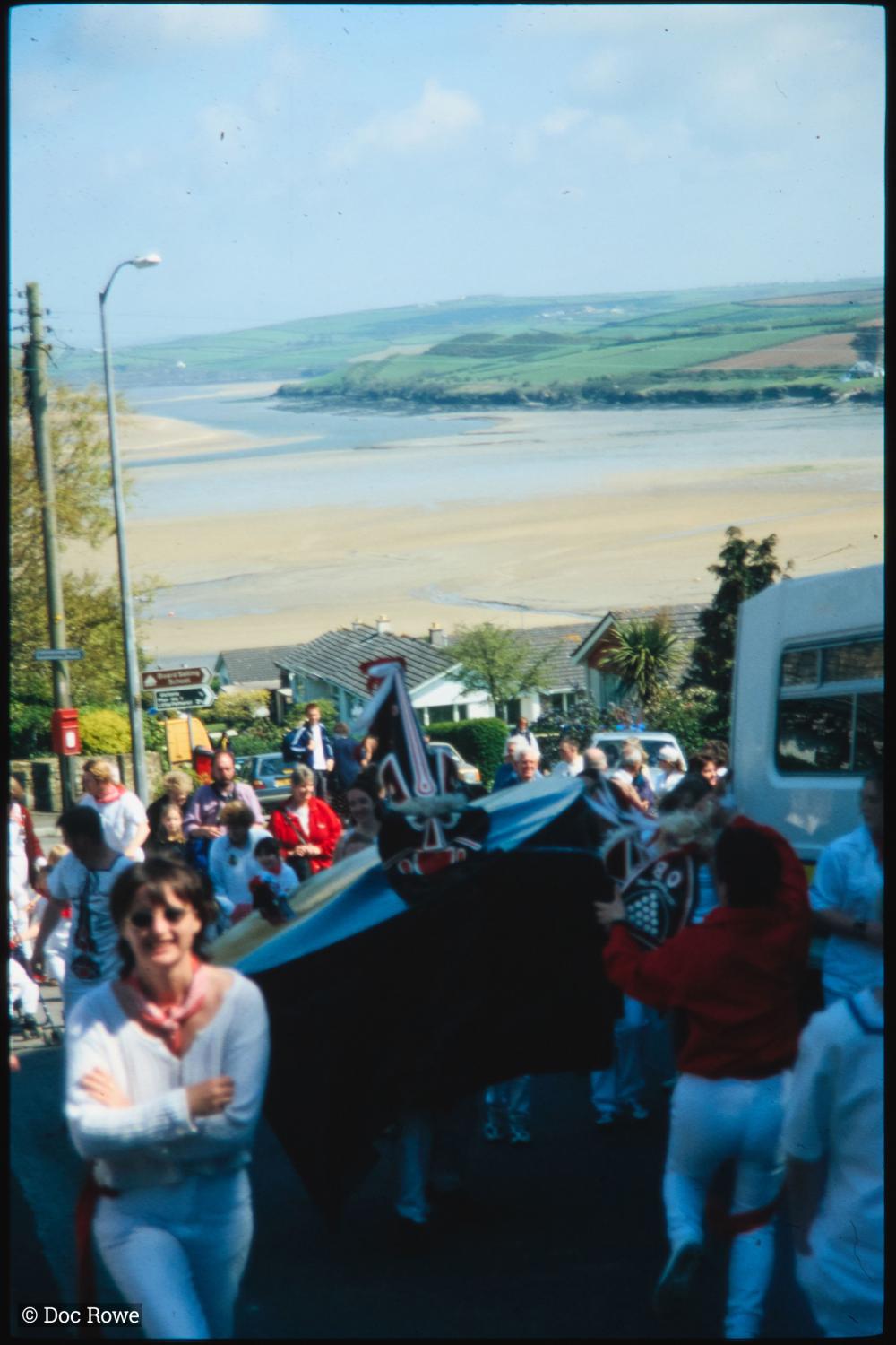 Old Oss walking up hill with view of sea in distance